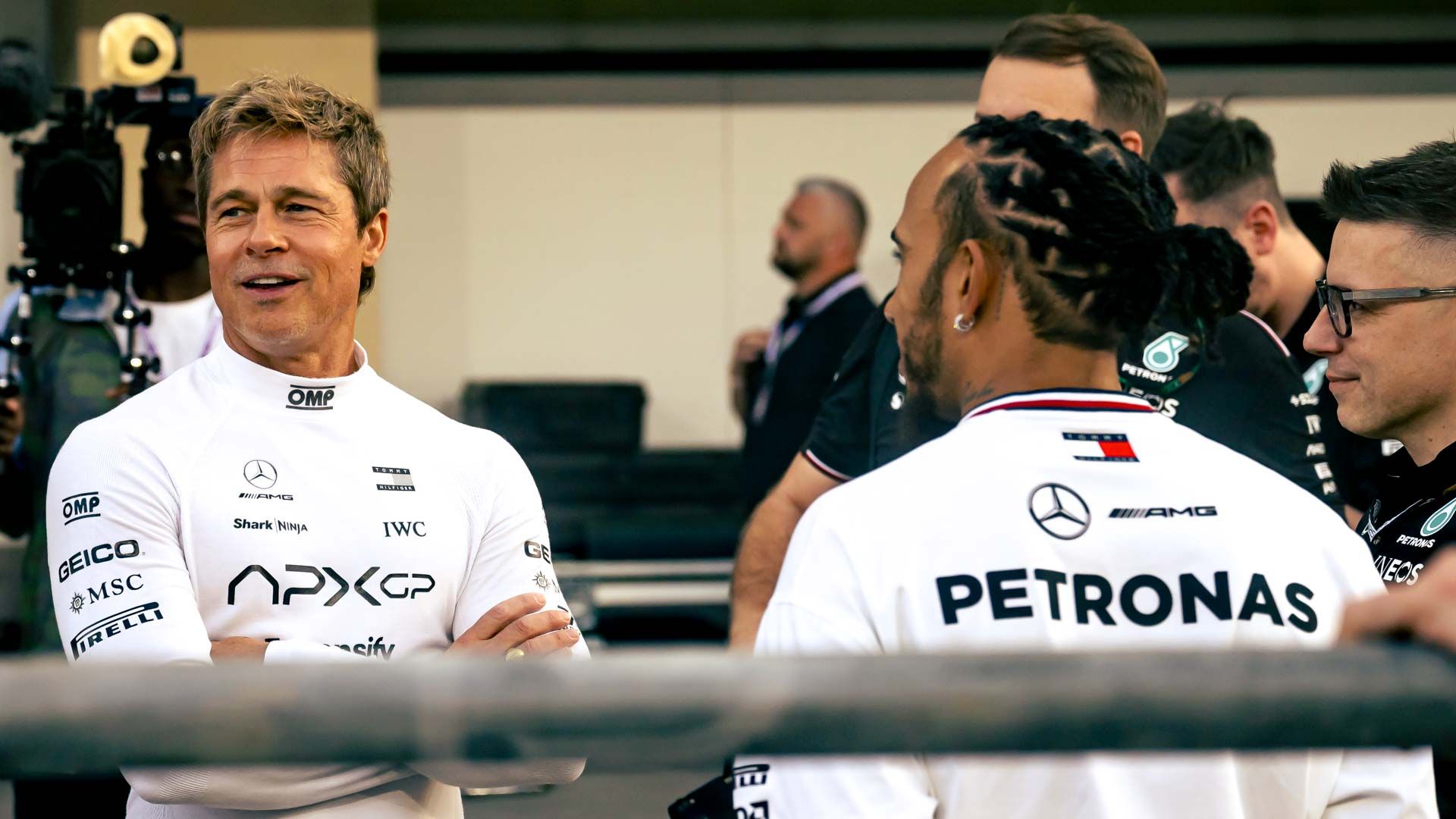 Actor Brad Pitt and Formula One driver Lewis Hamilton speaking together on the set of the Formula One (2025) movie.